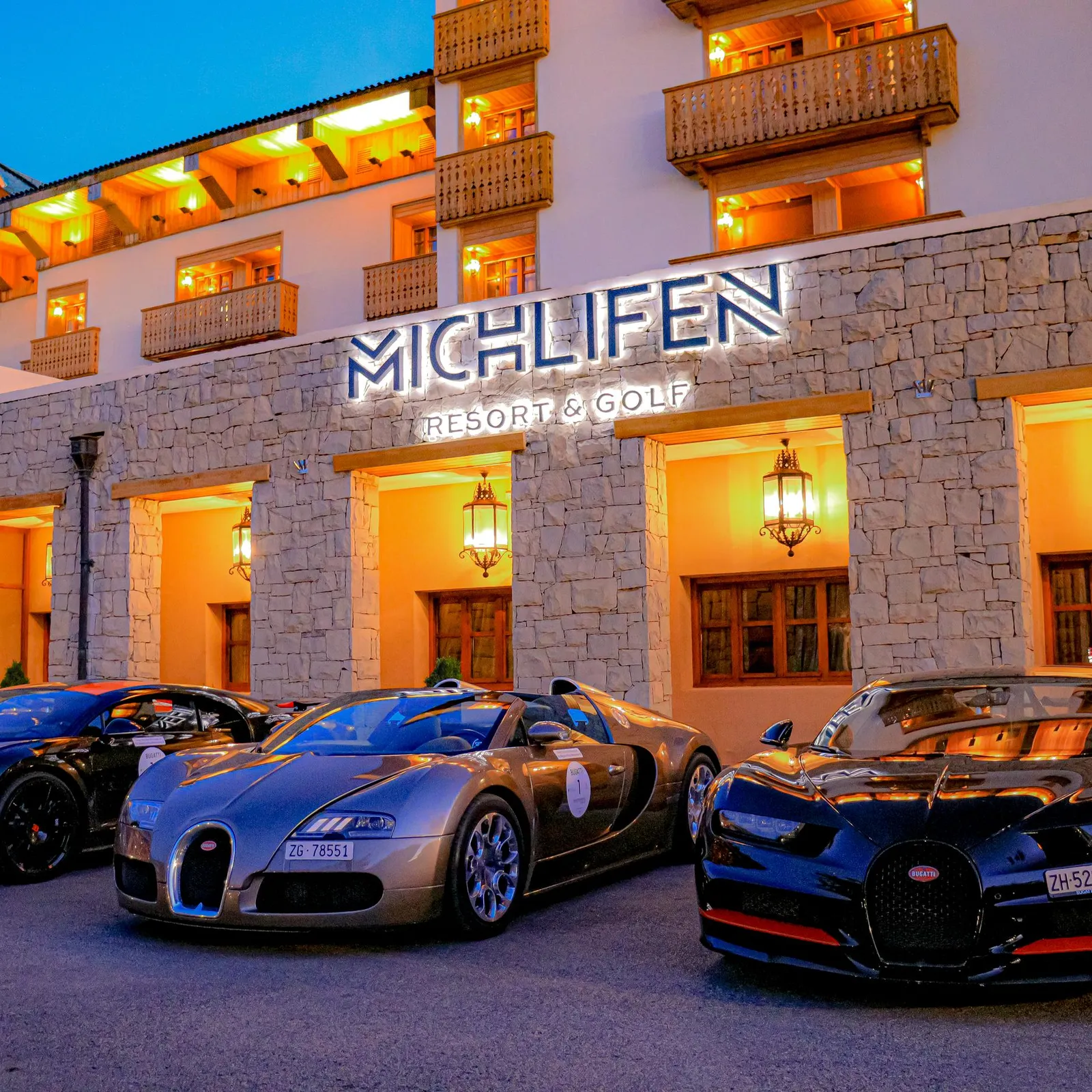 Quatre voitures de luxe sont garées devant l'entrée illuminée d'un hôtel nommé Michlifen Resort & Golf