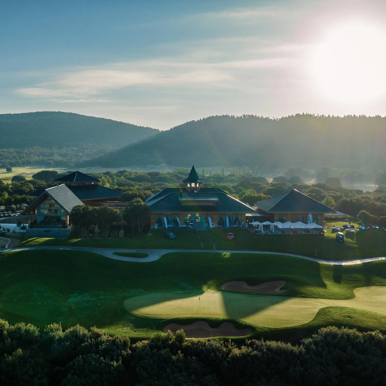Un terrain de golf avec des bâtiments et des montagnes en arrière-plan sous un ciel dégagé