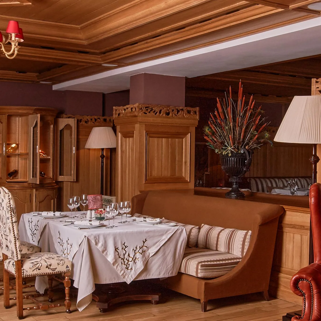 Salle à manger élégante avec table dressée, chandelier, lampes et canapés en cuir