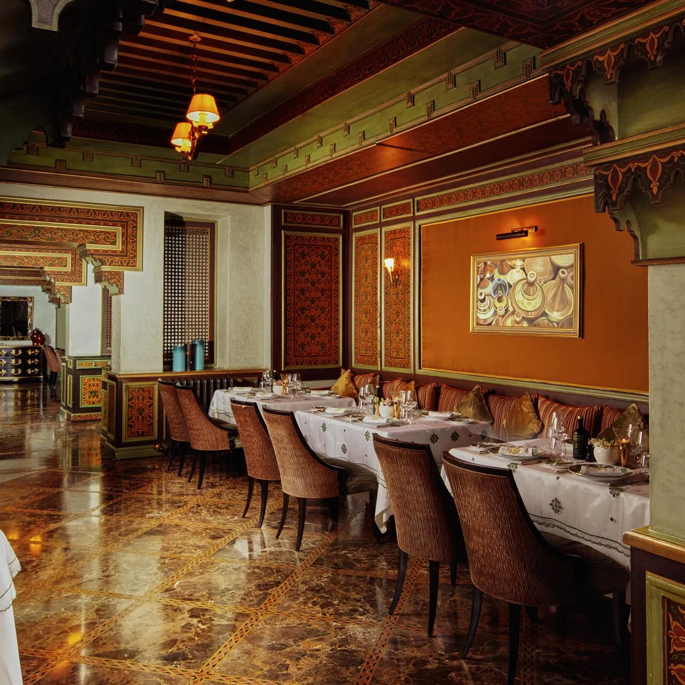 Restaurant élégant avec des tables dressées, des chaises rembourrées et des murs décorés de motifs traditionnels