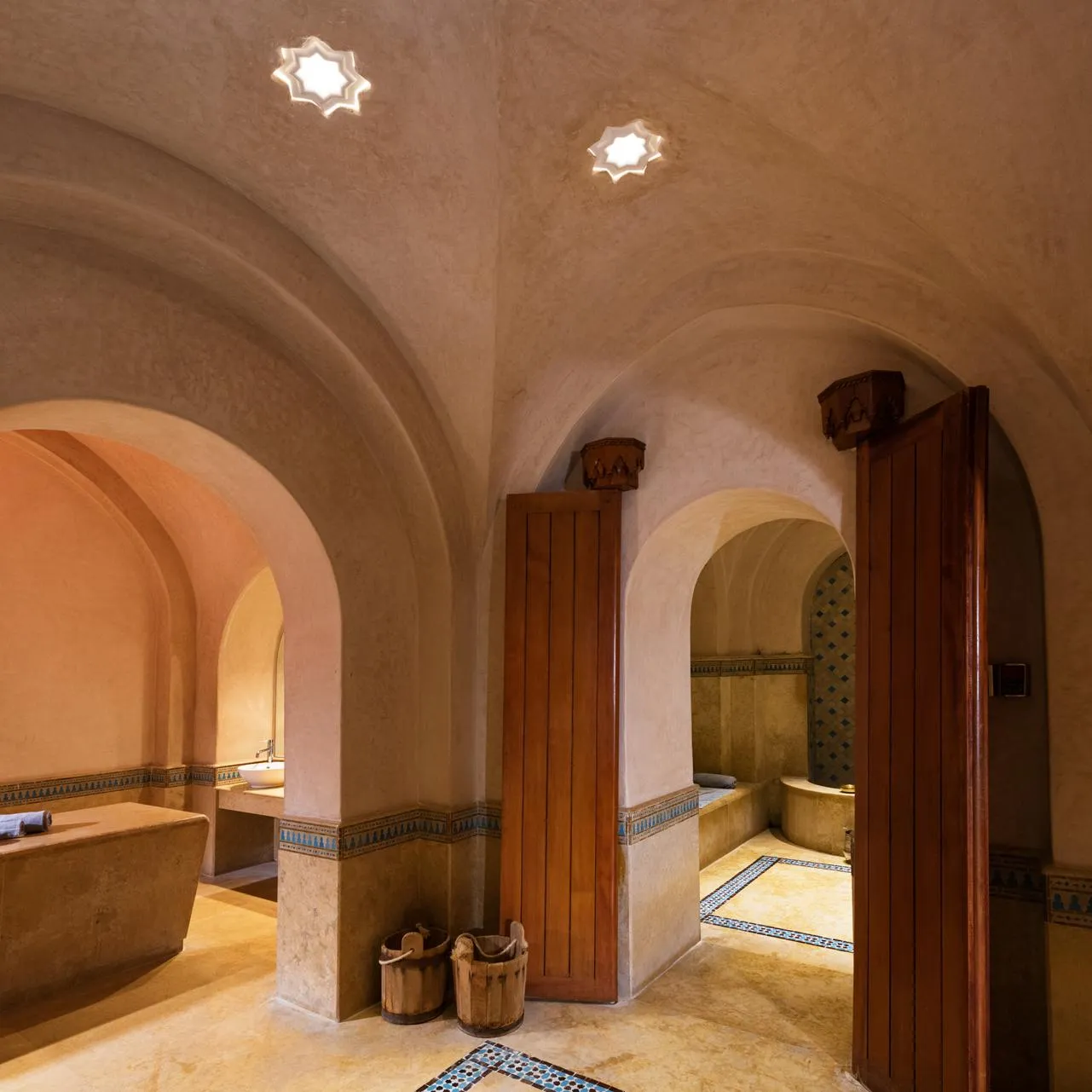 Salle aux arches et voûtes avec des bassins et des carreaux décoratifs au sol et sur les murs