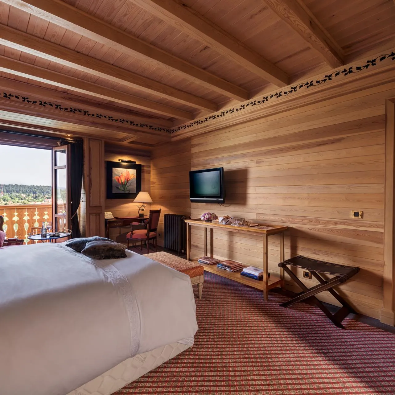 Chambre en bois avec deux lits, une télévision, un bureau et une vue sur l'extérieur par une porte-fenêtre