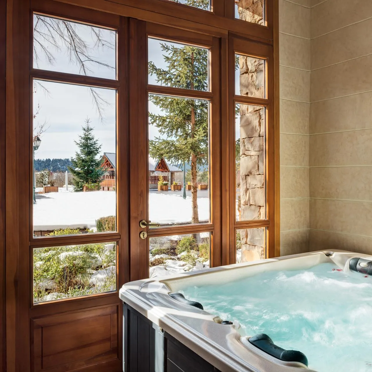 Jacuzzi rempli d'eau avec vue sur un paysage enneigé à travers de grandes fenêtres en bois