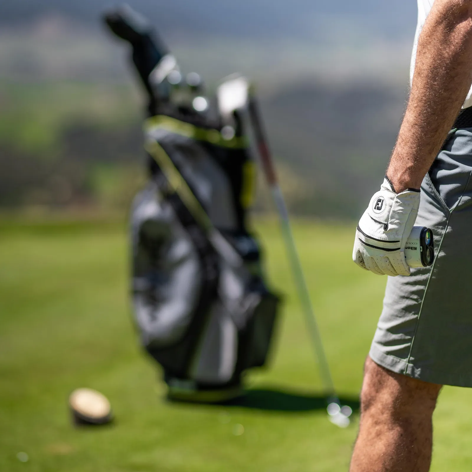 Un golfeur en action avec un sac de clubs en arrière-plan et une balle de golf au sol