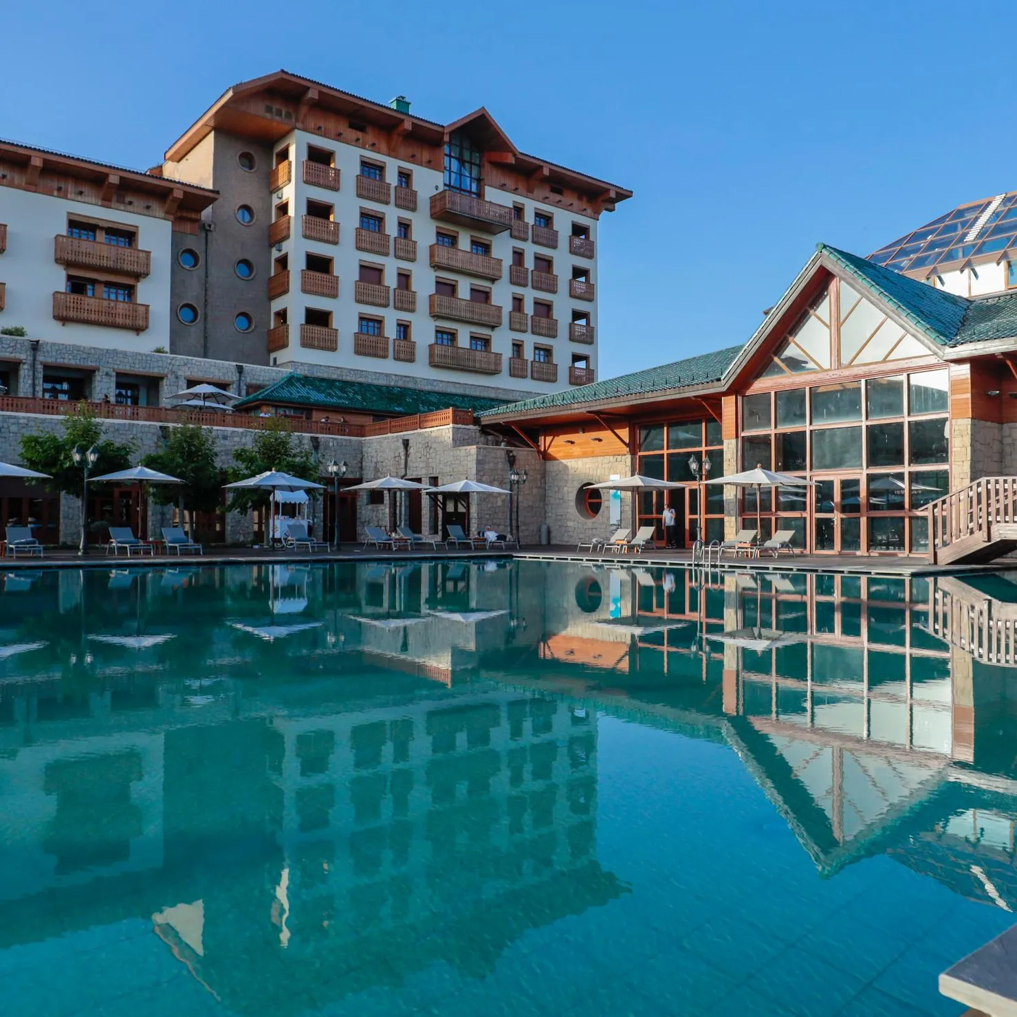 Un hôtel avec piscine extérieure, des chaises longues et des parasols sous un ciel dégagé