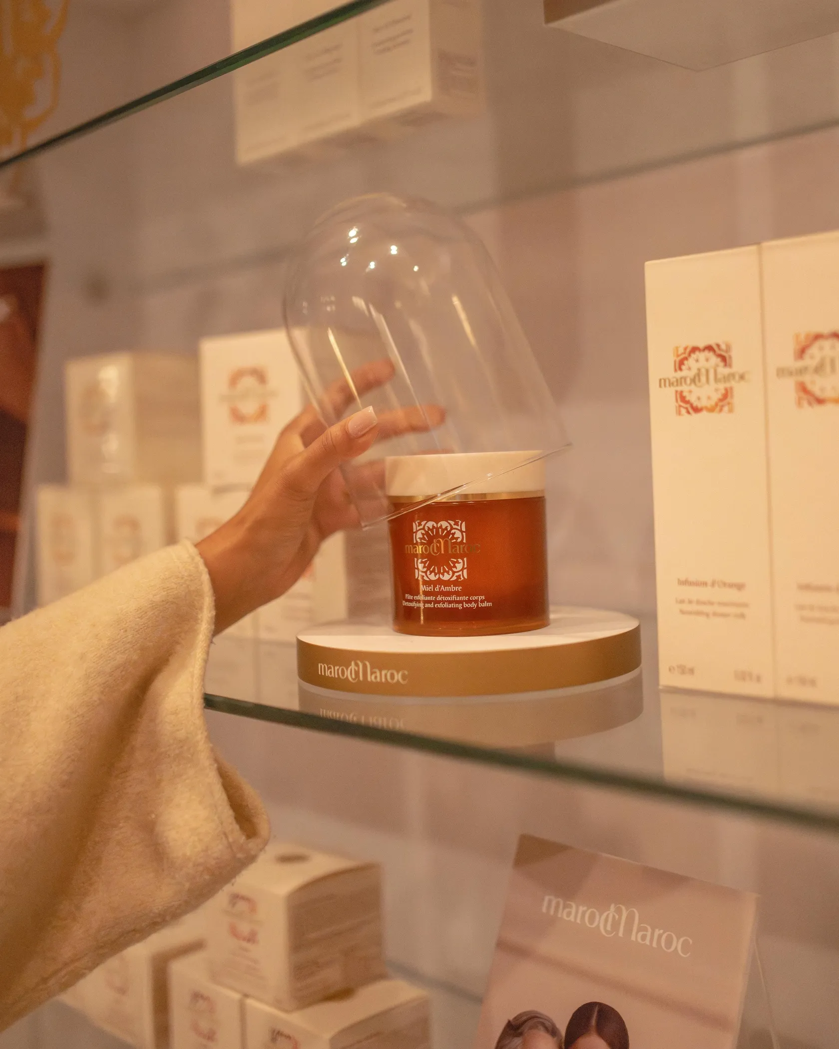 Une main tenant un verre de vin devant une vitrine de produits cosmétiques MarocMaroc