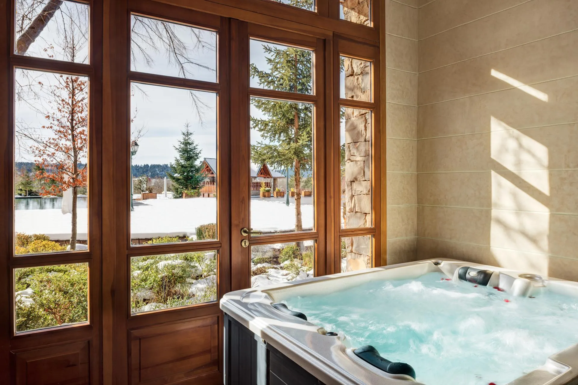 Jacuzzi rempli d'eau avec vue sur un paysage enneigé à travers de grandes fenêtres en bois