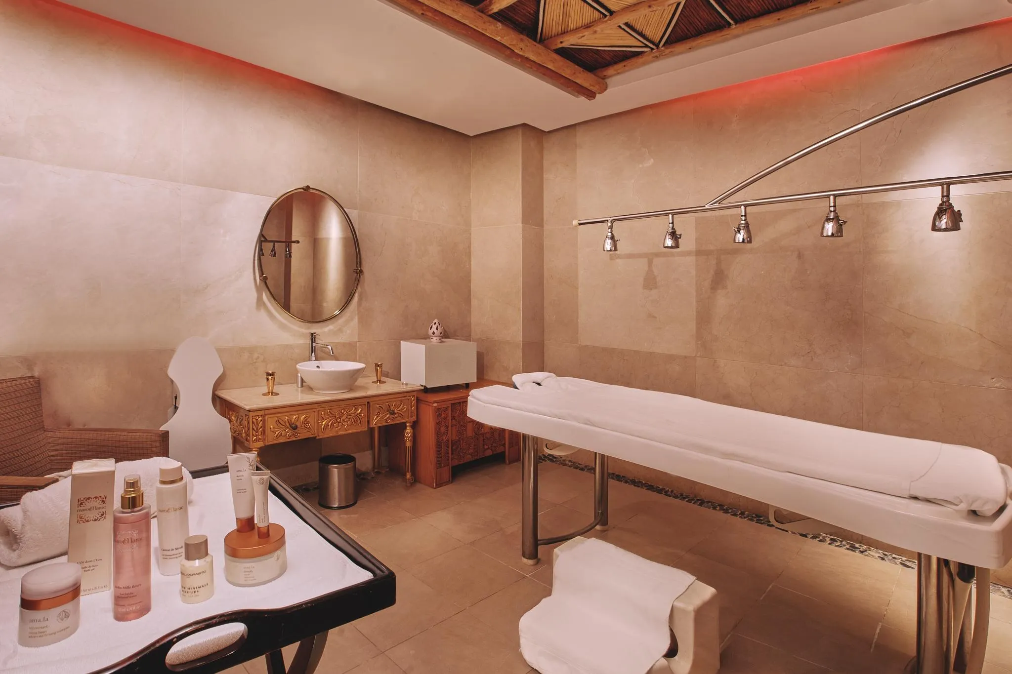 Salle de soins avec table de massage, miroir, lavabo et produits cosmétiques sur une table