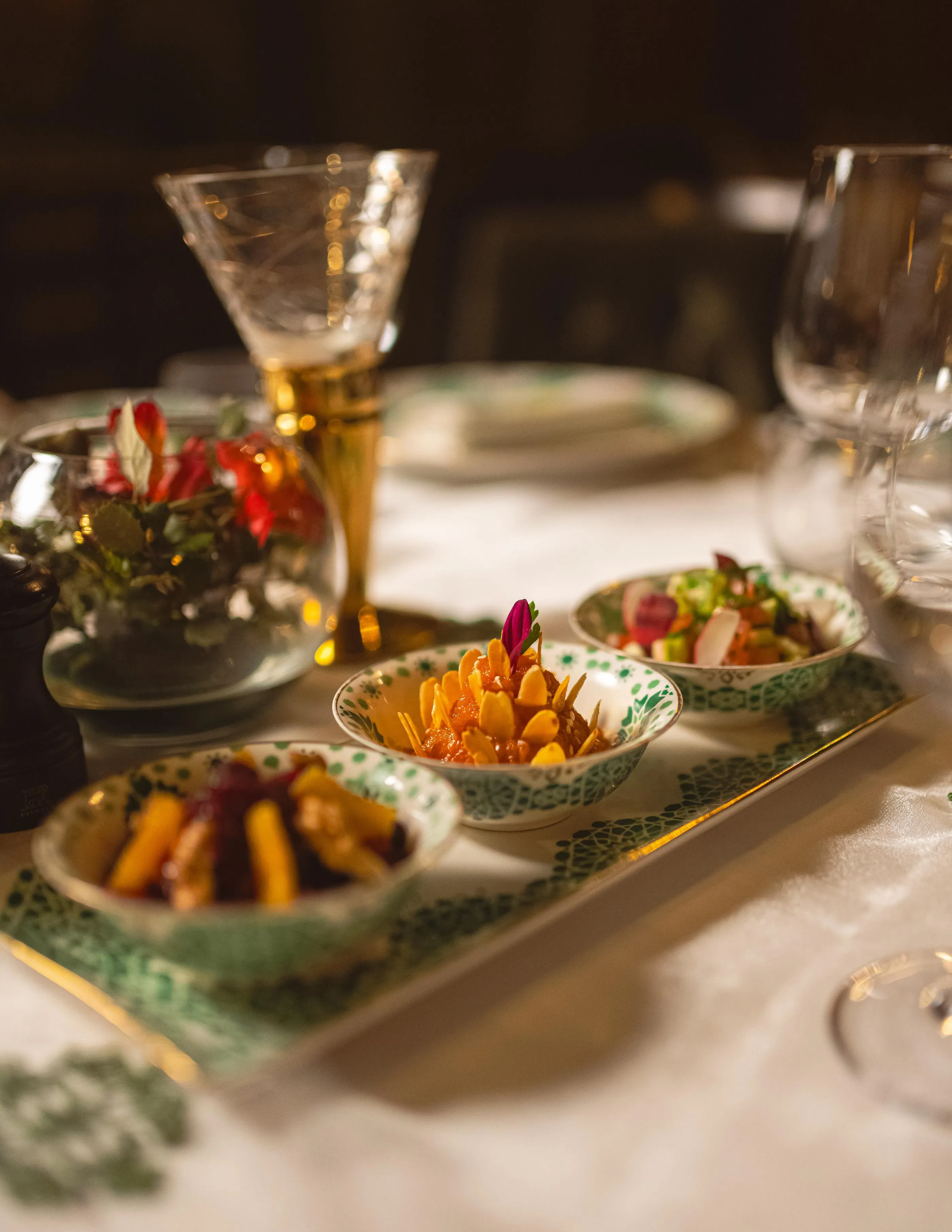 Assiettes de petits plats garnis de légumes et de fleurs, accompagnées de verres à cocktail sur une table