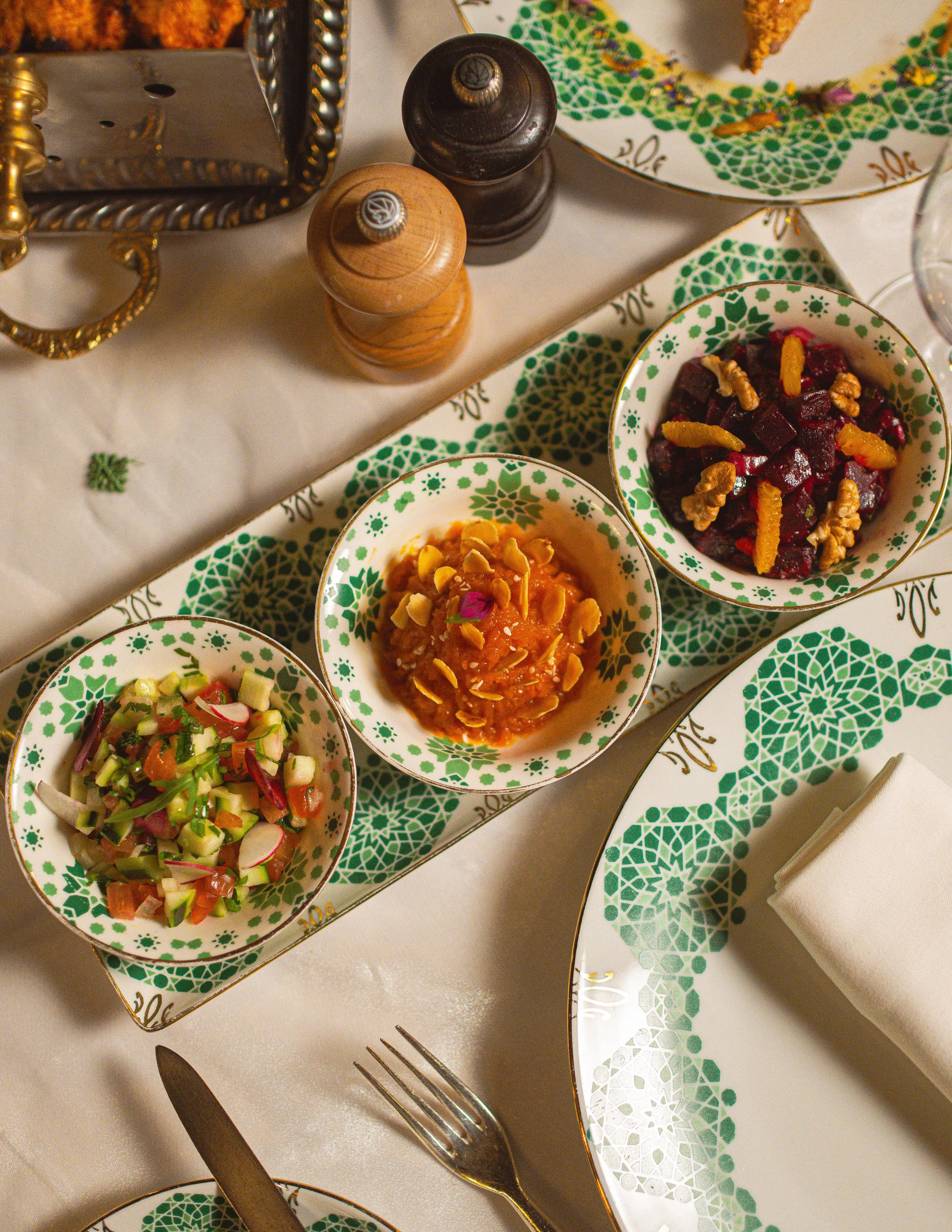 Trois petits bols de nourriture colorée sur une table avec des couverts et des épices