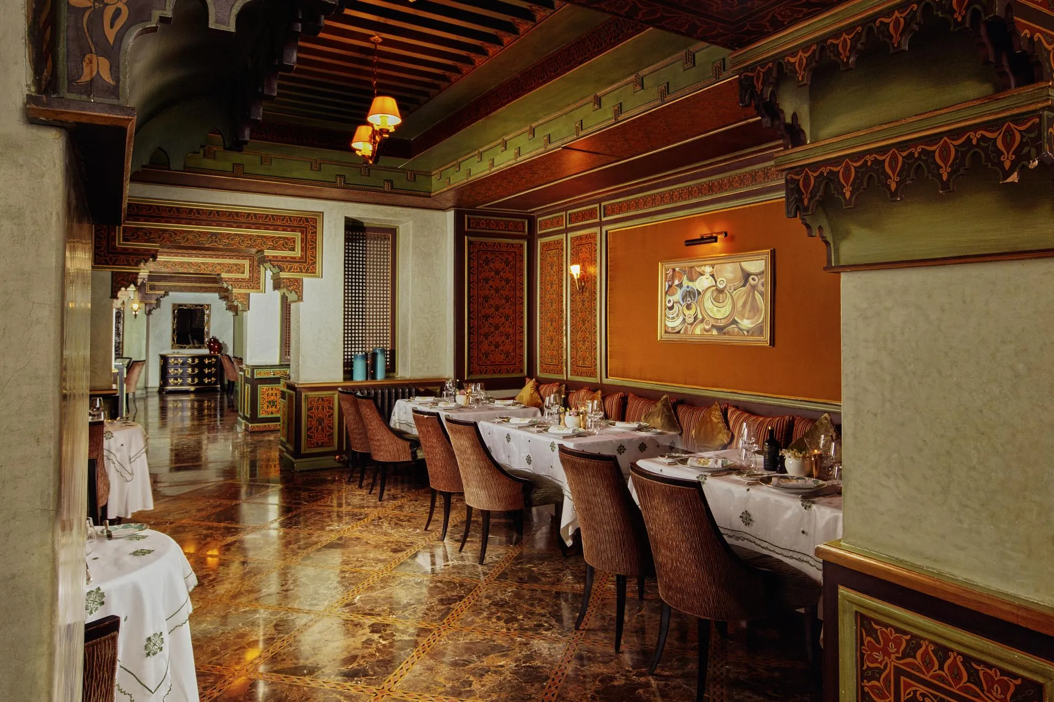 Restaurant élégant avec des tables dressées, des chaises rembourrées et des murs décorés de motifs traditionnels
