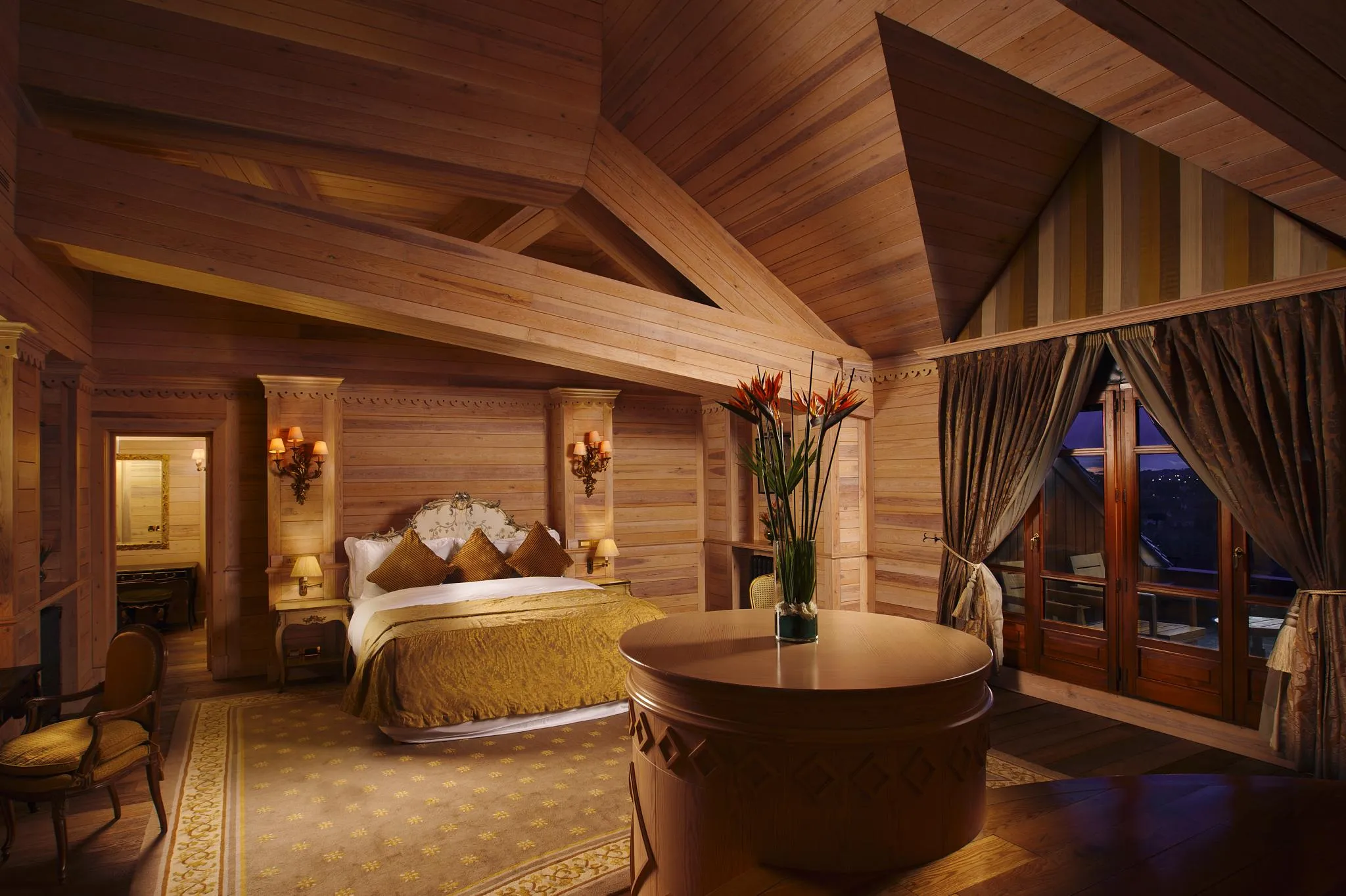 Chambre en bois avec un lit à baldaquin, une table ronde et des fenêtres avec des rideaux