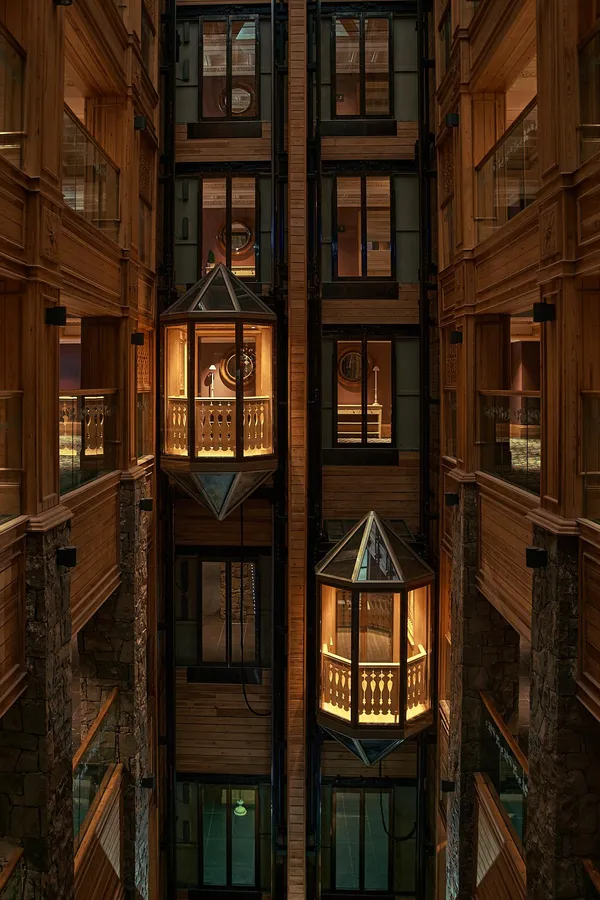 Vue verticale d'un atrium intérieur avec des balcons en bois éclairés et des fenêtres vitrées