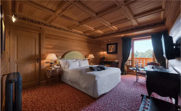 Chambre en bois avec un lit double, des tables de chevet, un bureau, des rideaux ouverts et une vue sur l'extérieur