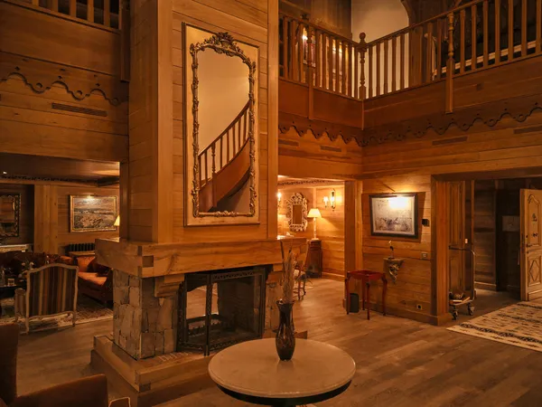 Intérieur en bois avec escalier, cheminée et miroir orné
