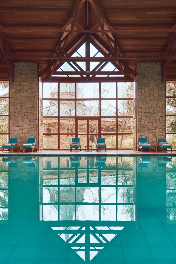 Piscine intérieure avec vue sur des fenêtres et des chaises longues à travers une grande baie vitrée