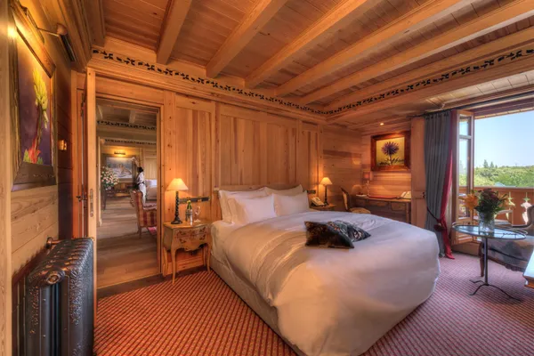 Chambre en bois avec un grand lit, une table de chevet, une fenêtre ouverte et une vue sur l'extérieur
