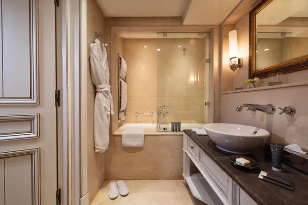 Salle de bain avec baignoire, lavabo, miroir, serviettes et peignoirs suspendus