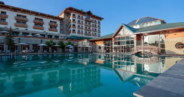 Un hôtel avec piscine extérieure, des chaises longues et des parasols sous un ciel dégagé